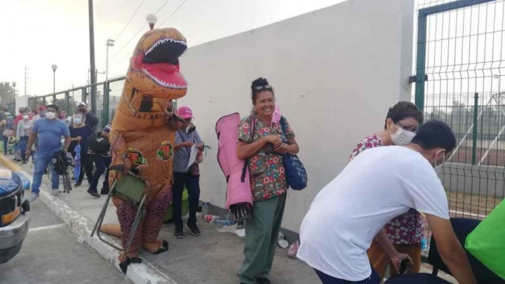 “Dinosaurio” acompaña a su mamá a vacunarse contra COVID-19.