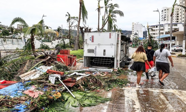 Vecinos caminan entre los escombros en una calle afectada por el huracán Otis