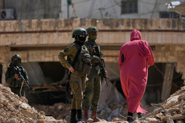Residentes del campamento de refugiados palestinos de Tulkarem, Cisjordania, regresan a recoger sus pertenencias ante la vigilancia de militares israelíes, el jueves 29 de mayo de 2025.