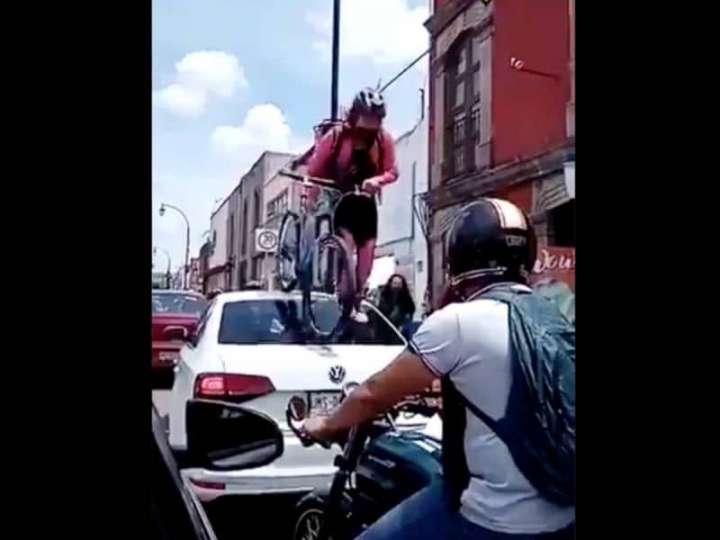 Joven pasa con todo y bici por encima de auto.