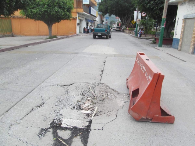  Vallas naranjas previenen a los vecinos que tengan cuidado porque el pavimento está deteriorado y se está hundiendo.